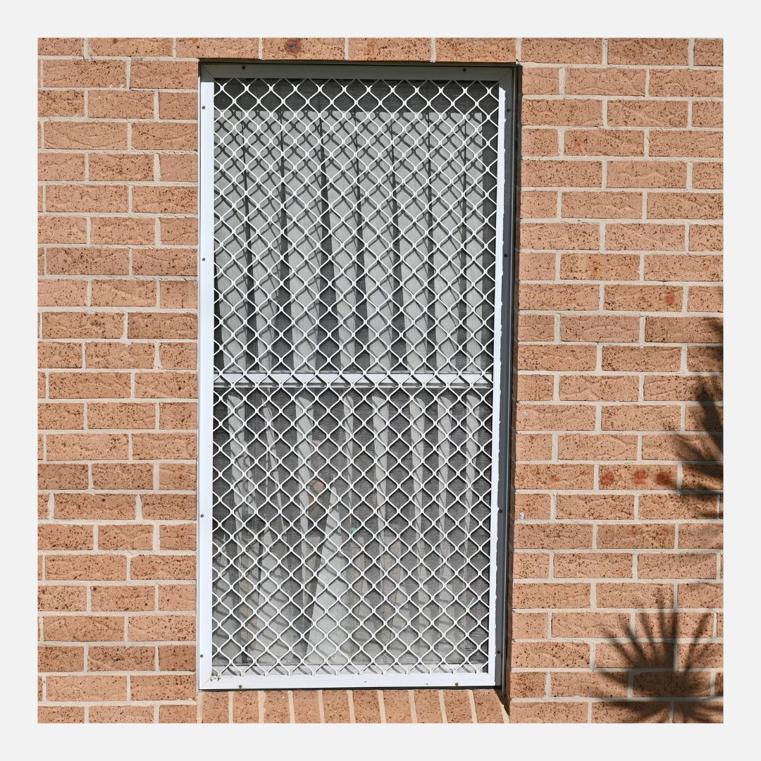 Security screen over a window in a brick building.
